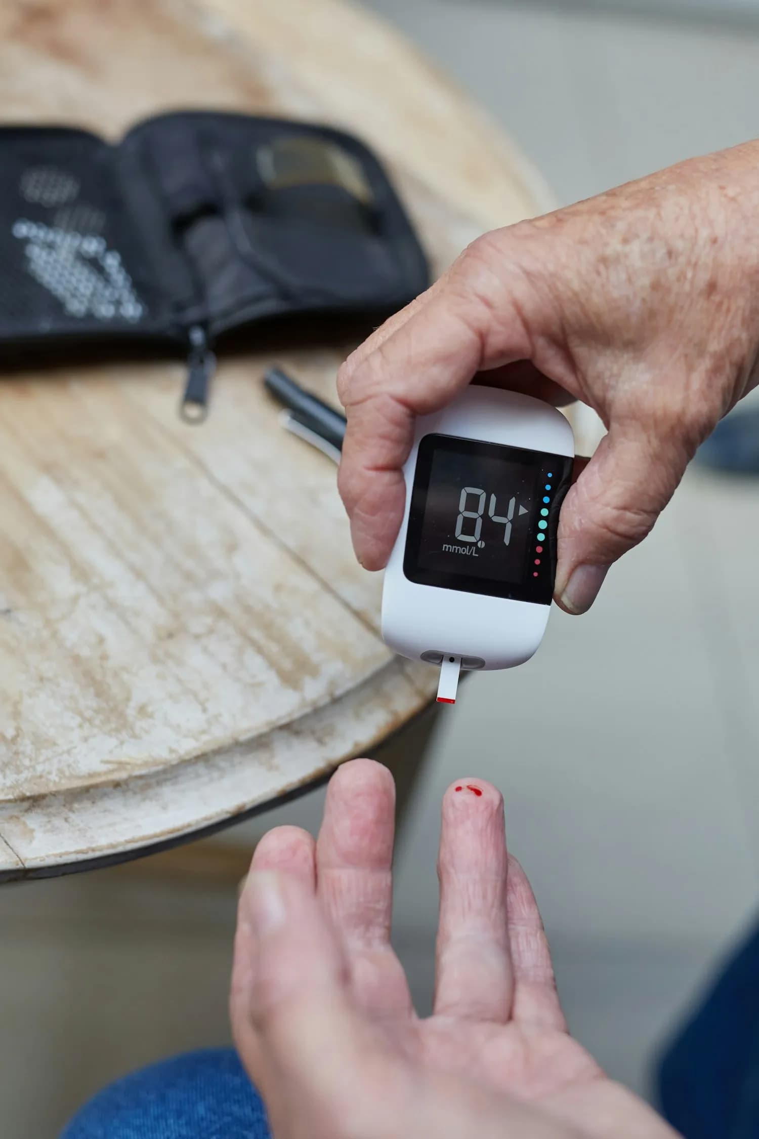 Hands holding a blood glucose meter showing a reading