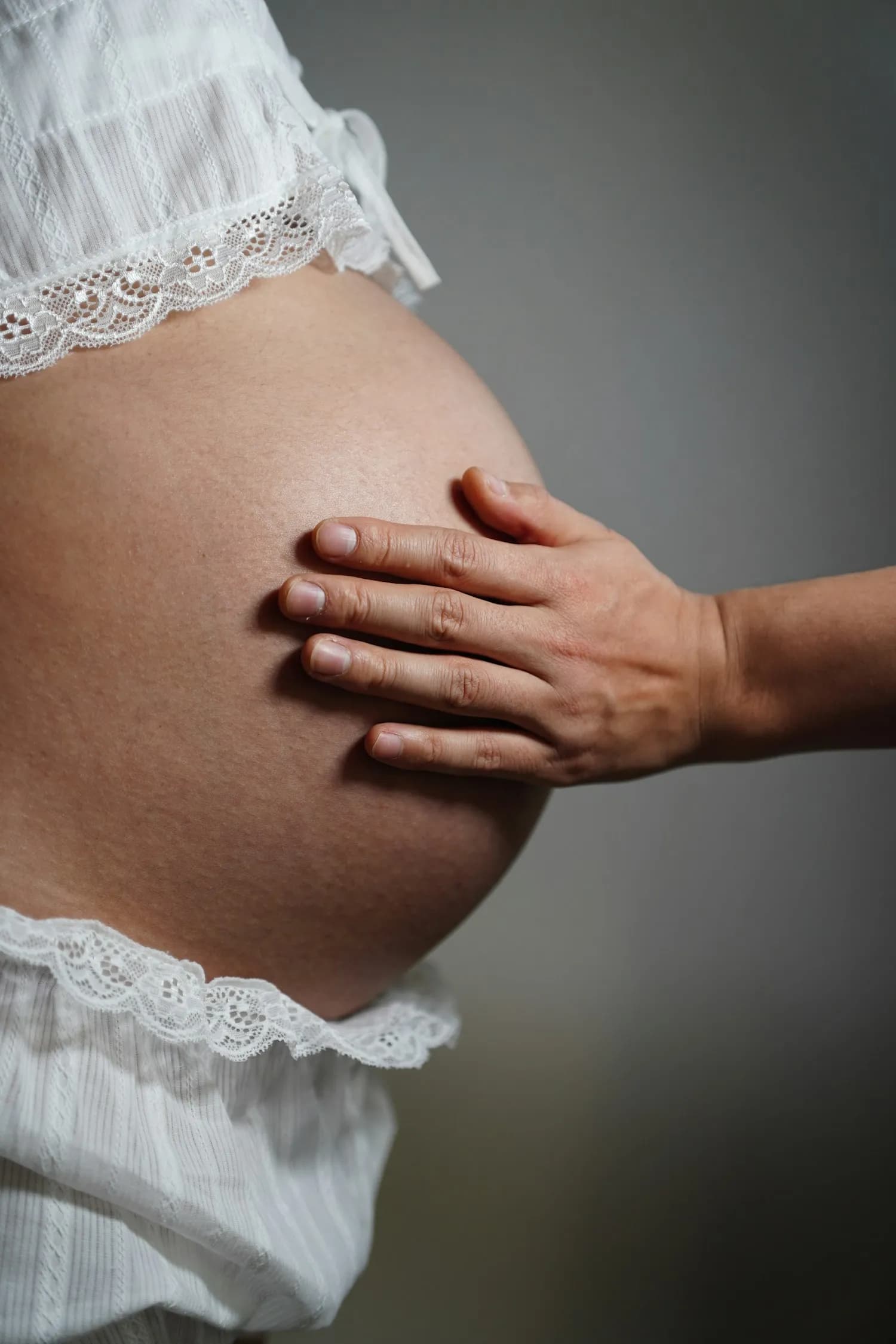 A hand resting gently on a pregnant belly