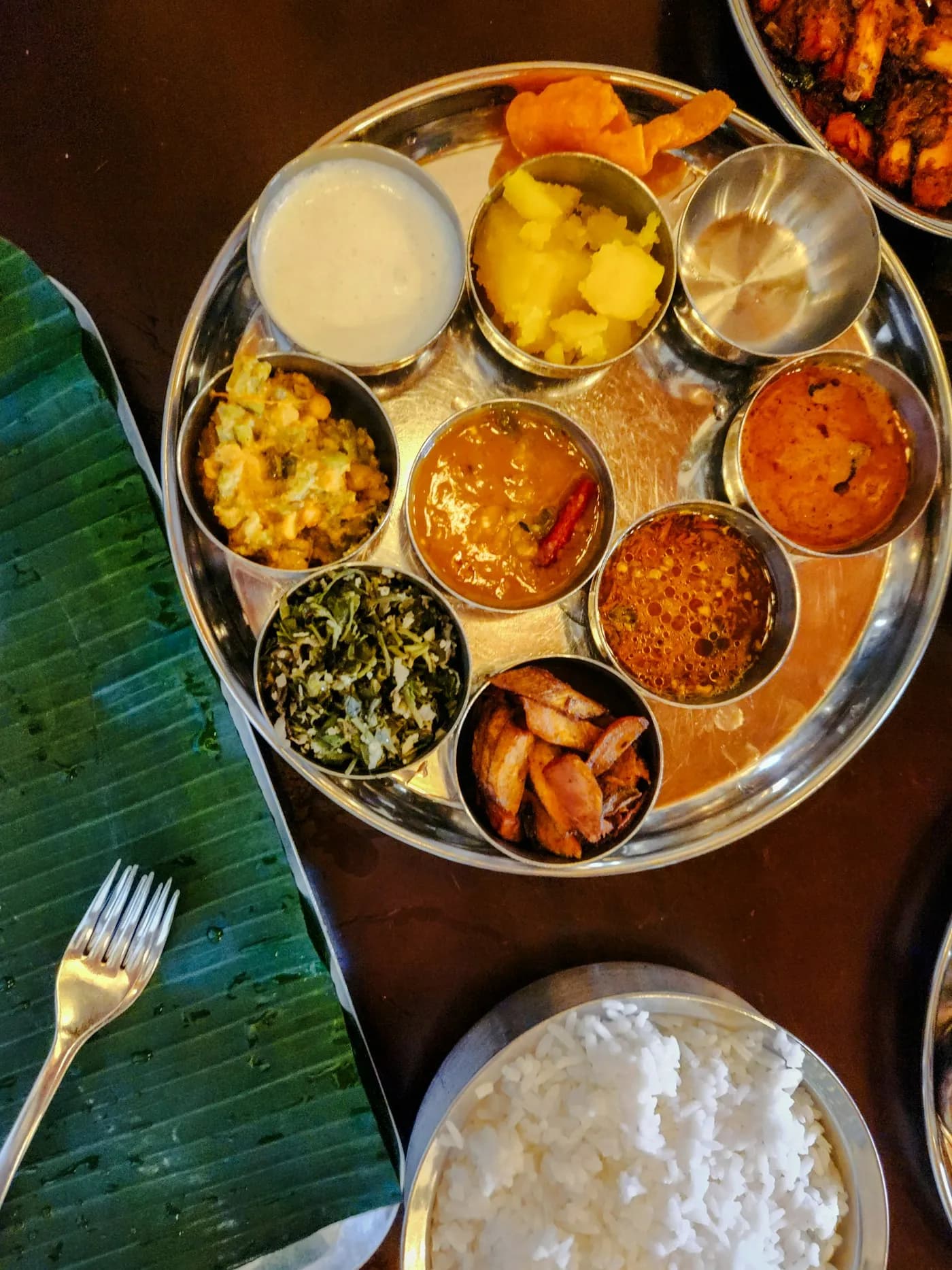 A steel thali with dal, sabzi, rice and accompaniments seen from above